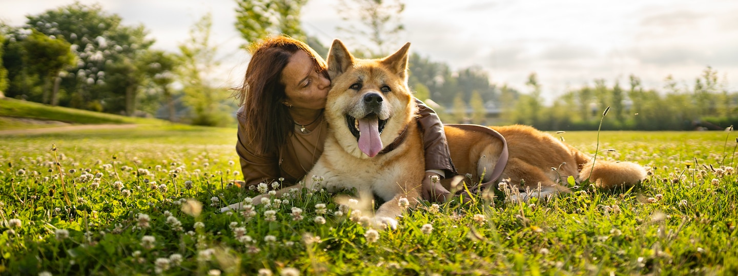 woman snuggling dog in a field